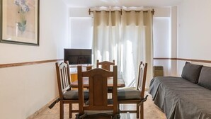 A room with a bed, a wooden dining table with chairs, a television, and a window with curtains. - Concord Rent Apart (Córdoba)