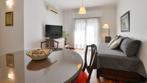 A modern living room with a glass dining table, a sofa, a TV, and a lamp. - Concord Rent Apart (Córdoba)