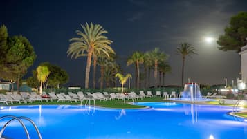 Una piscina con tumbonas y palmeras.
