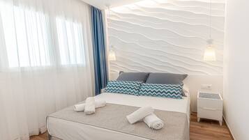 Habitació d'hotel moderna amb un llit ben fet, una taula de nit i una paret amb un relleu decoratiu.