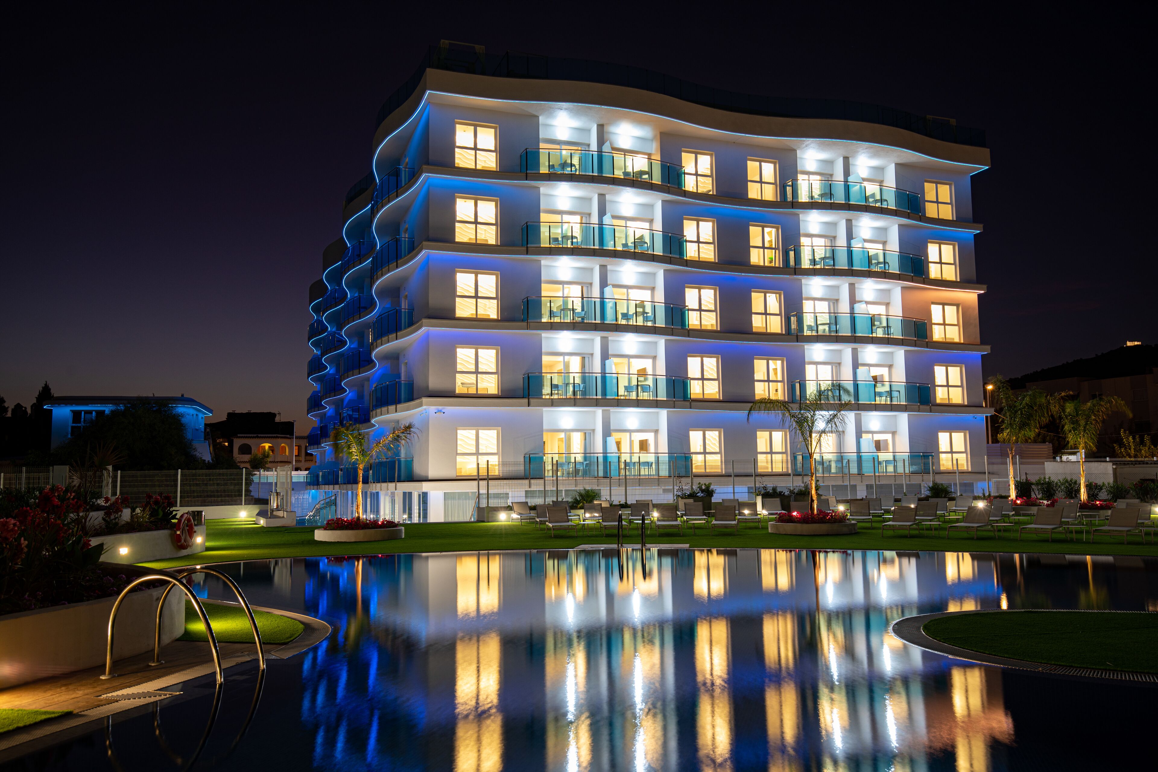 A multi-story hotel with balconies and a swimming pool in the foreground.
