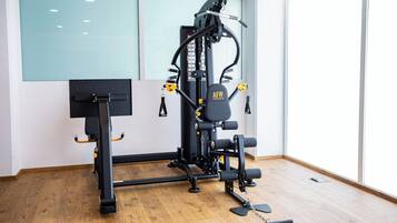 A gym with a multi-functional workout machine, a pull-up bar, and a yoga mat on the floor.