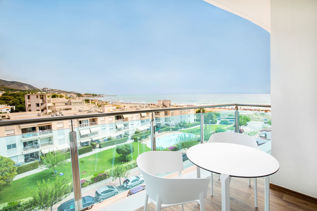 Un balcón con vistas al mar, una piscina y edificios circundantes.