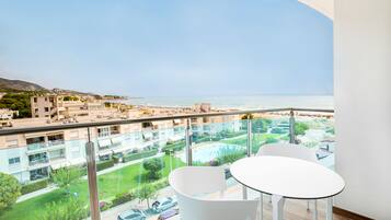 Ein Balkon mit Blick auf einen Strand und ein Schwimmbad.