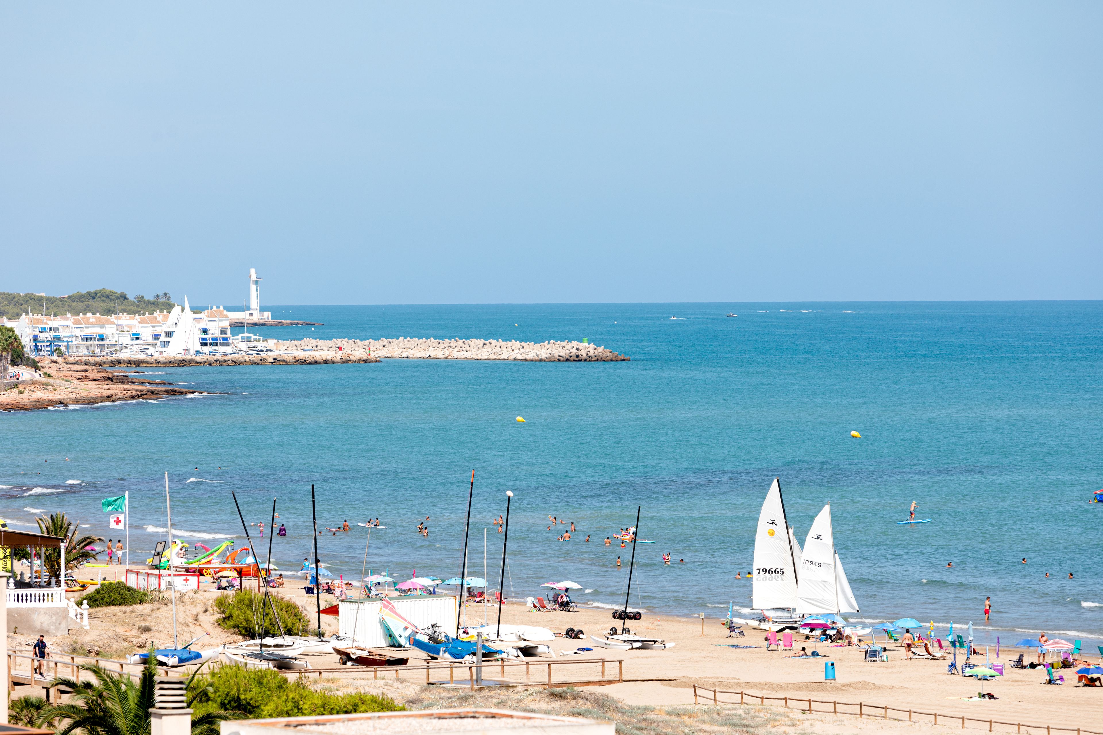 A beach with boats, umbrellas, and people.