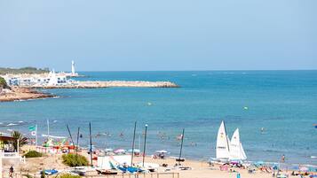 Une plage avec des bateaux, des parasols et des gens.