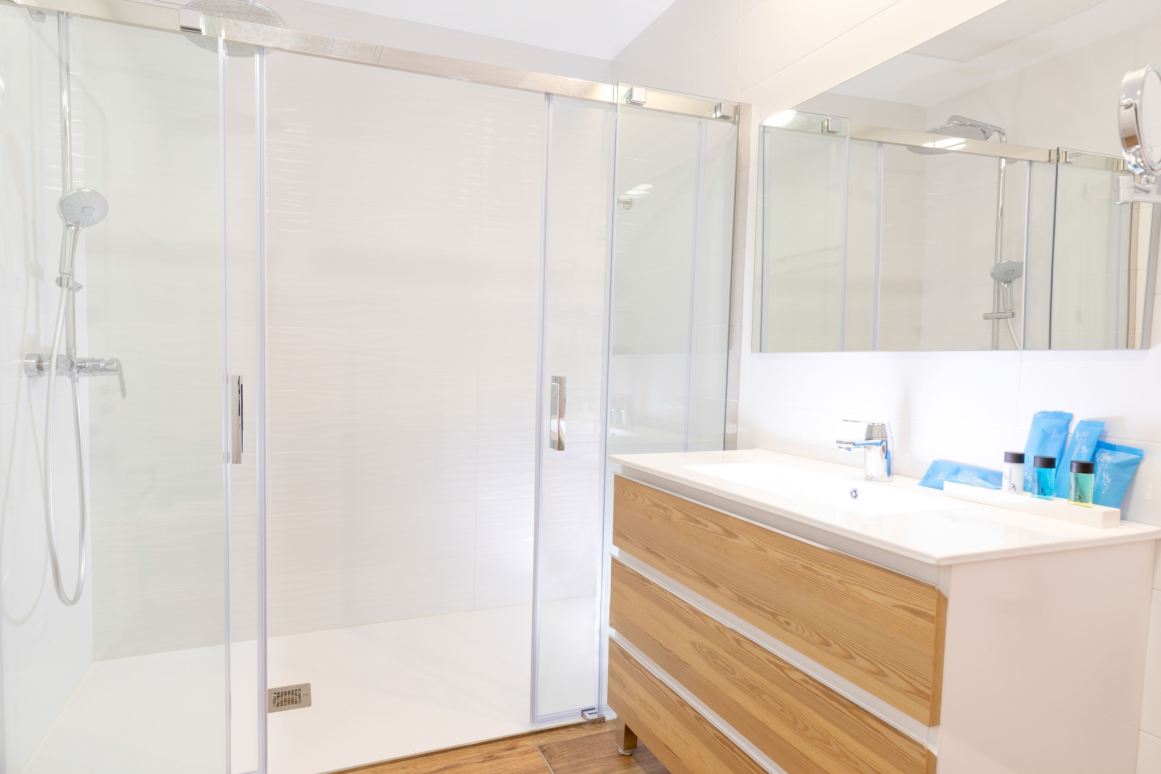 A modern bathroom with a glass-enclosed shower, a wooden vanity with a sink, and a large mirror above the vanity.