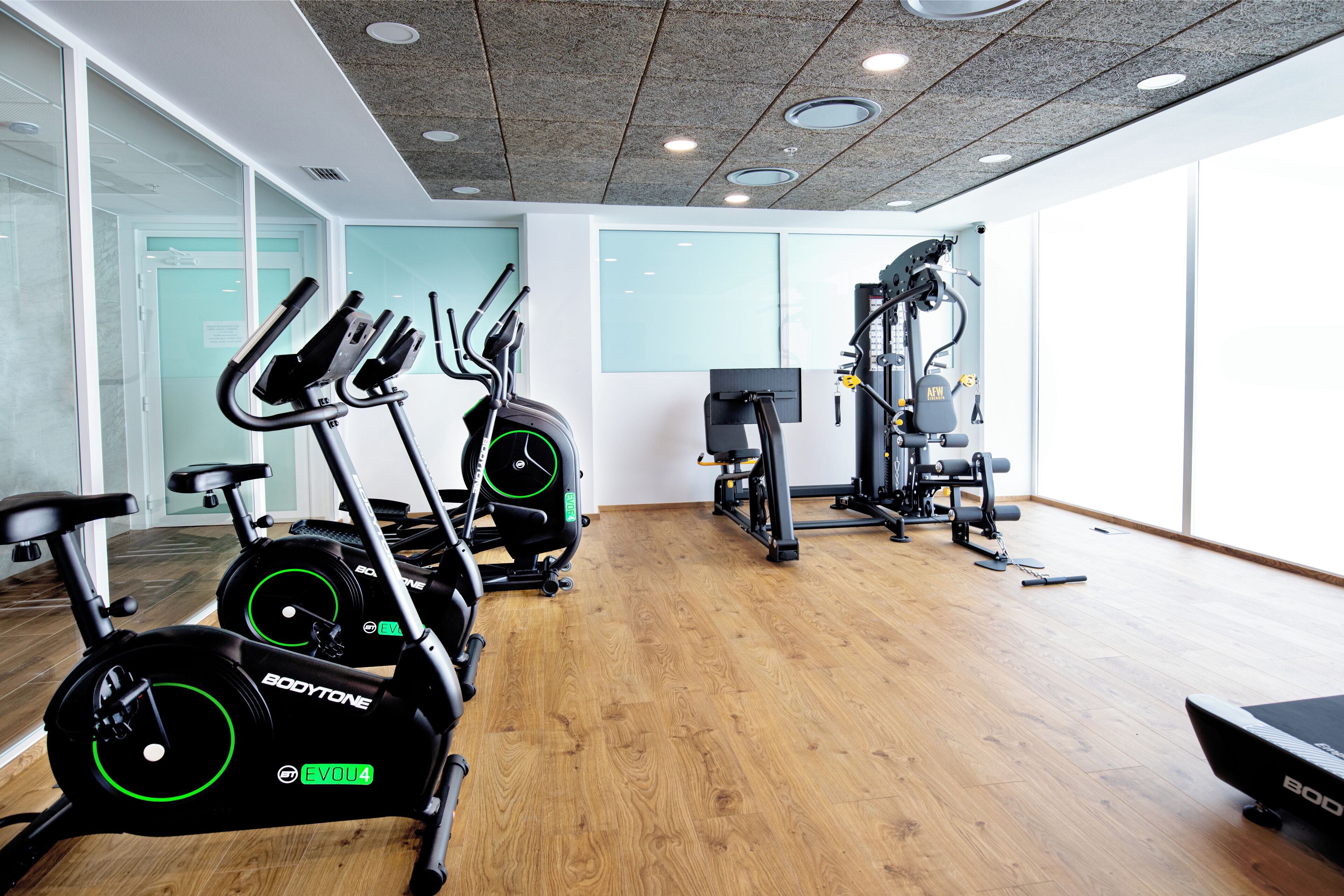 Un gimnasio con bicicletas estáticas, una cinta de correr y máquinas de pesas.
