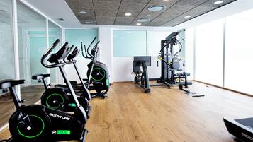 Un gimnasio con bicicletas estáticas, una cinta de correr y máquinas de pesas.