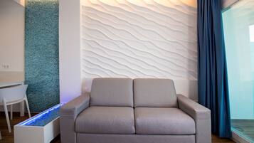 Ein modernes Wohnzimmer mit einer Couch, einer weißen Wand mit einer strukturierten Oberfläche, einer blauen Akzentwand und einer Glastrennwand.
