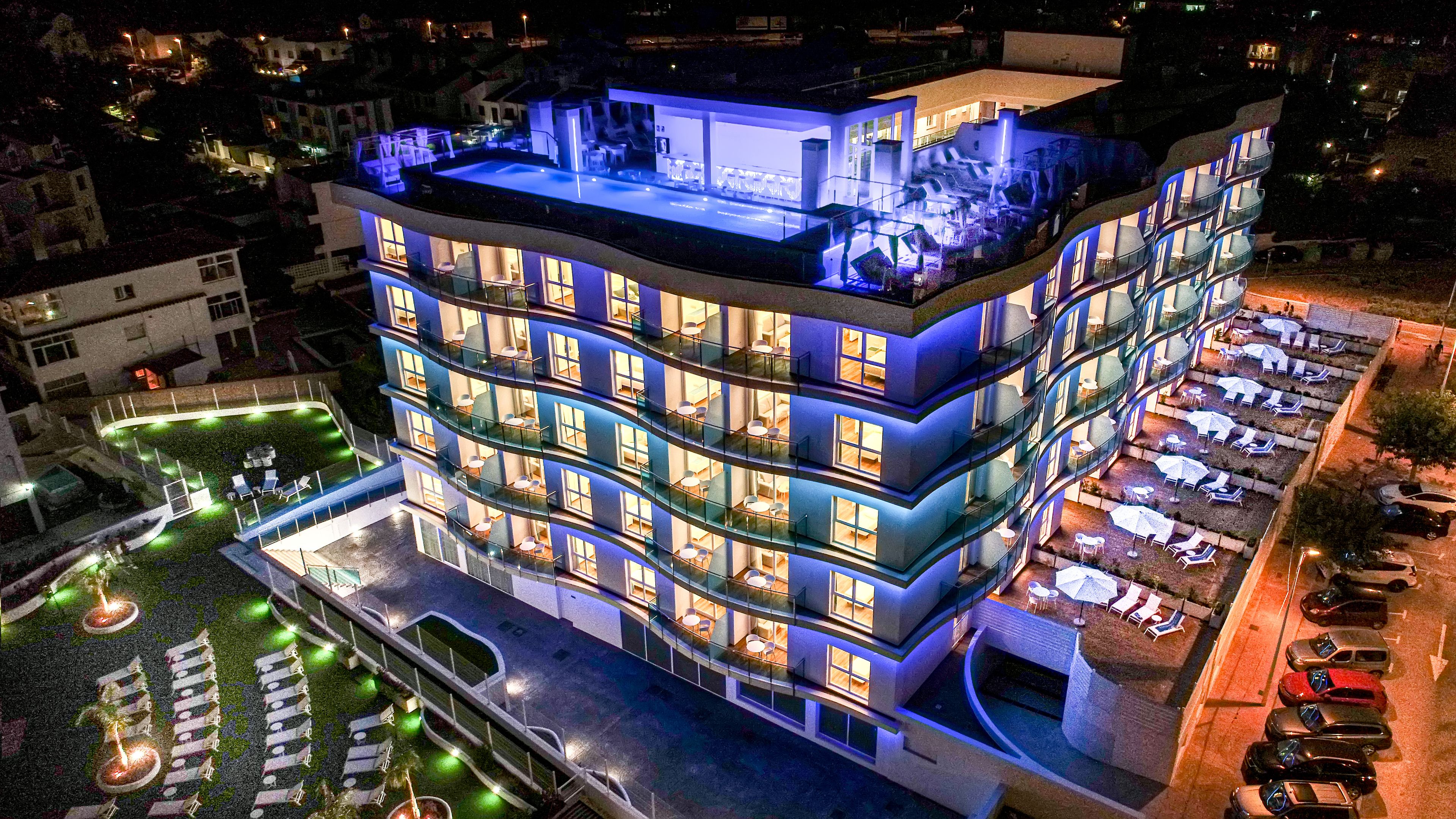 Un hotel de varios pisos con piscina en la azotea y zonas de estar al aire libre.