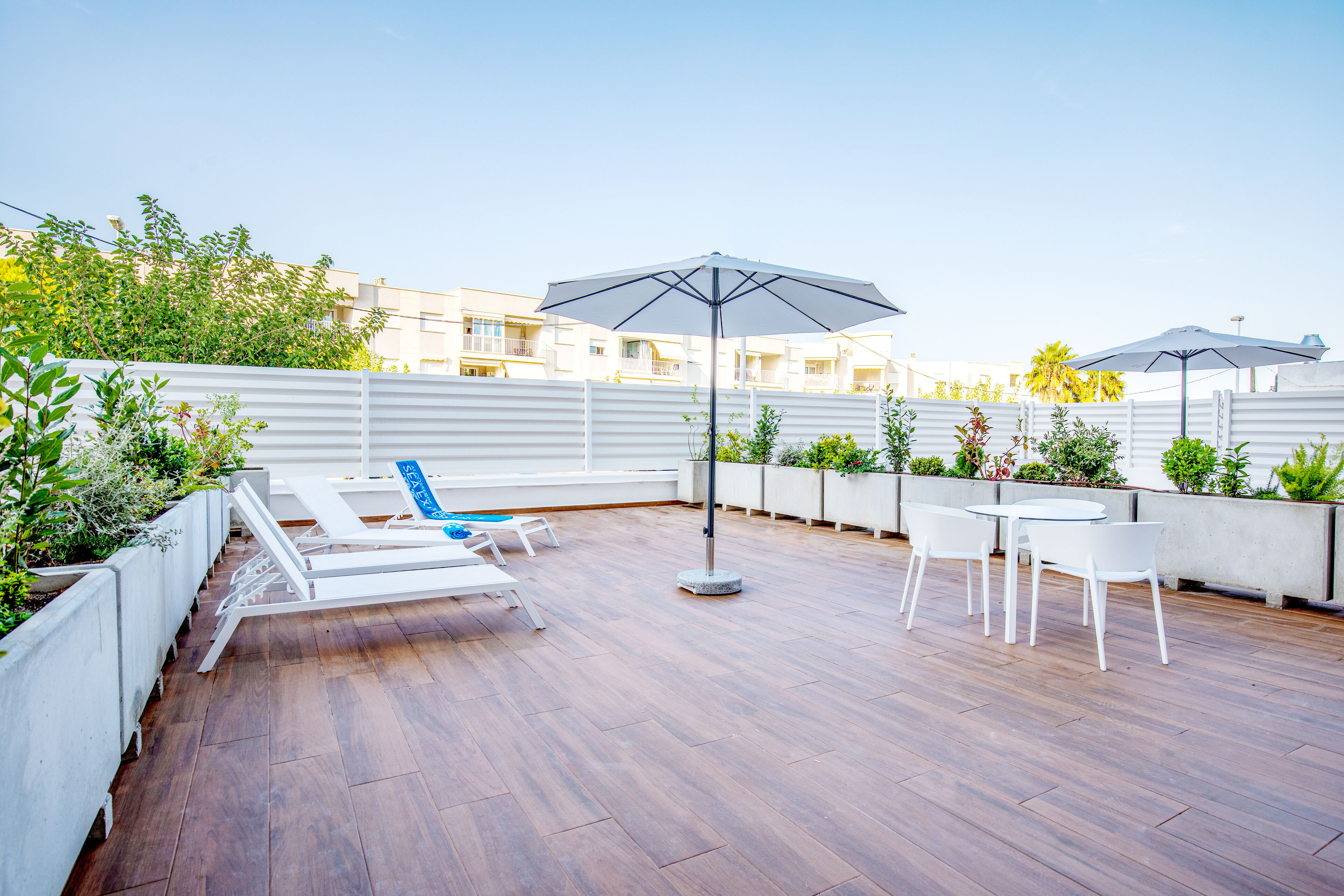 A rooftop patio with lounge chairs, a table, and umbrellas.
