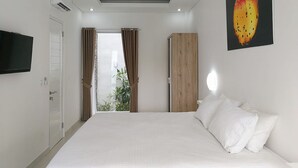 Quarto de hotel moderno com uma cama grande, guarda-roupa, televisão na parede e janela com cortinas.