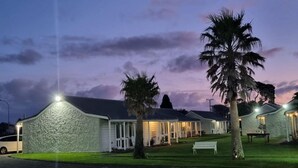 A row of white buildings with stone facades, each with a porch and a bench.