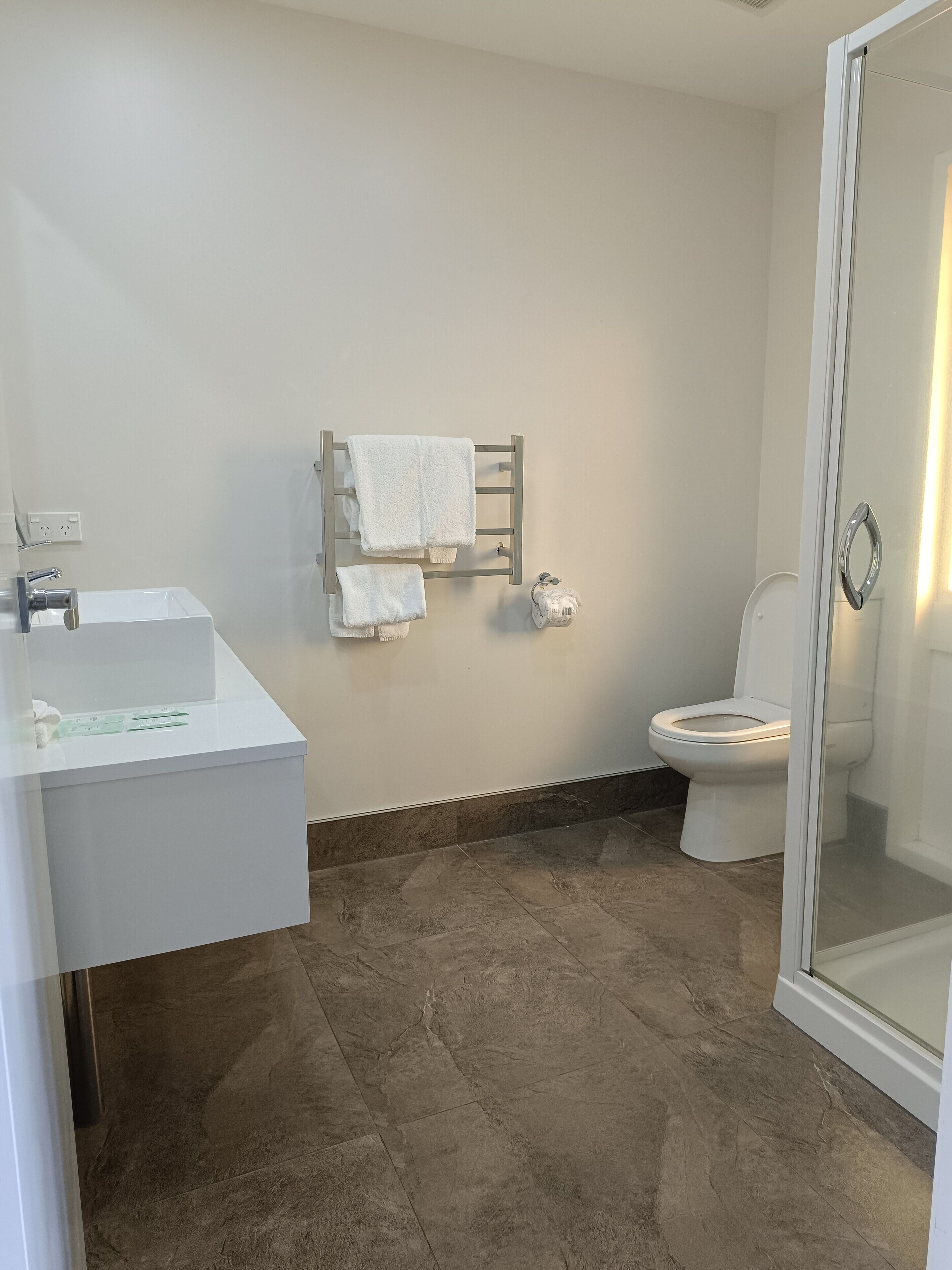 A bathroom with a white sink, a toilet, and a glass shower enclosure.