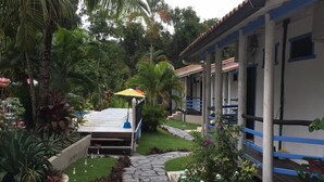 Un hotel con un área de estar al aire libre techada, palmeras y un sendero de piedra.