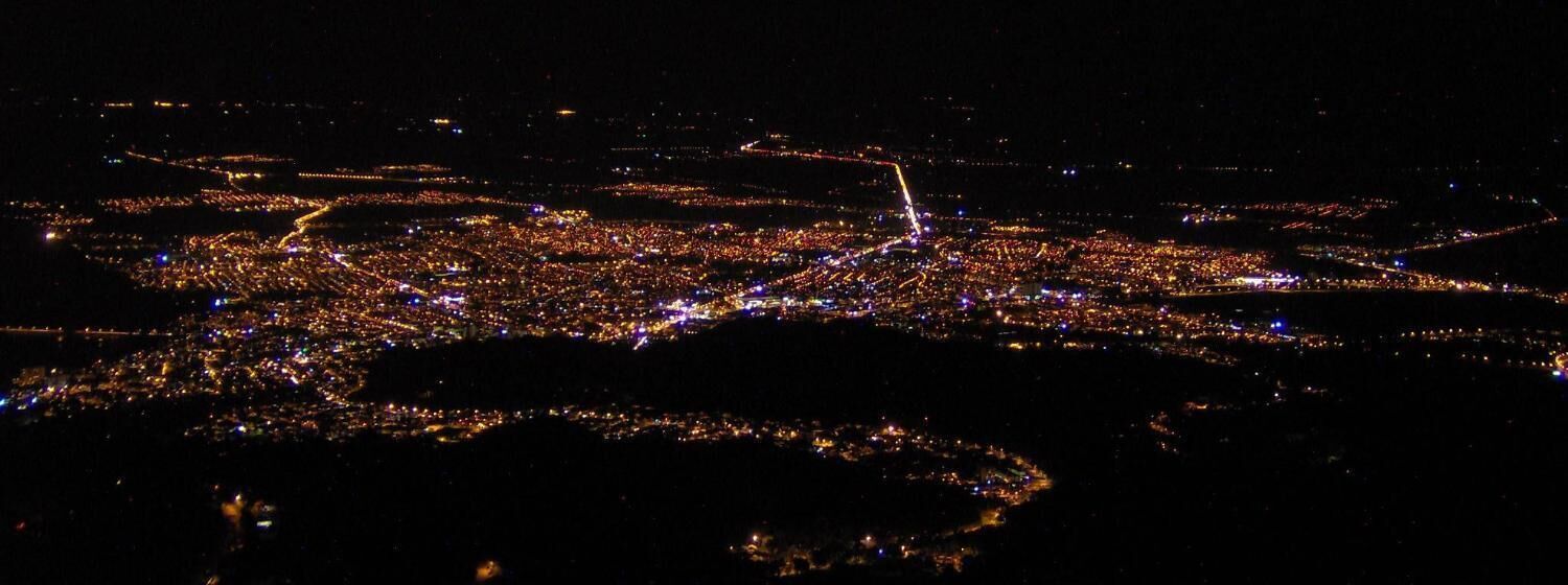 An aerial view of a city at night with illuminated streets and buildings.