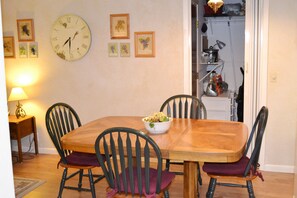 Cozy dining area with a wooden table and four chairs, a wall clock, and framed artwork.