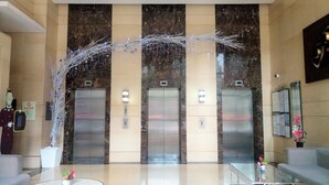 Un hall d’entrée doté de trois ascenseurs, d’un comptoir de réception et d’une arche décorative.