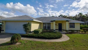 A two-story house with a garage, a front porch, and a well-maintained lawn. - Villa Lovie - Comfort - 4 Bedroom (Inverness)
