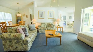 A spacious living room with floral-patterned furniture, a coffee table, and two lamps. - Villa Lovie - Comfort - 4 Bedroom (Inverness)