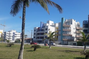A modern building with multiple floors, balconies, and a clear blue sky.