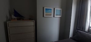A room with a bed, a dresser, and two framed pictures on the wall.