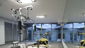 Een moderne sportschool met cardioapparaten en gewichten, grote ramen en een strak, minimalistisch ontwerp.