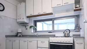 Een keuken met witte kastjes, een fornuis en een raam.