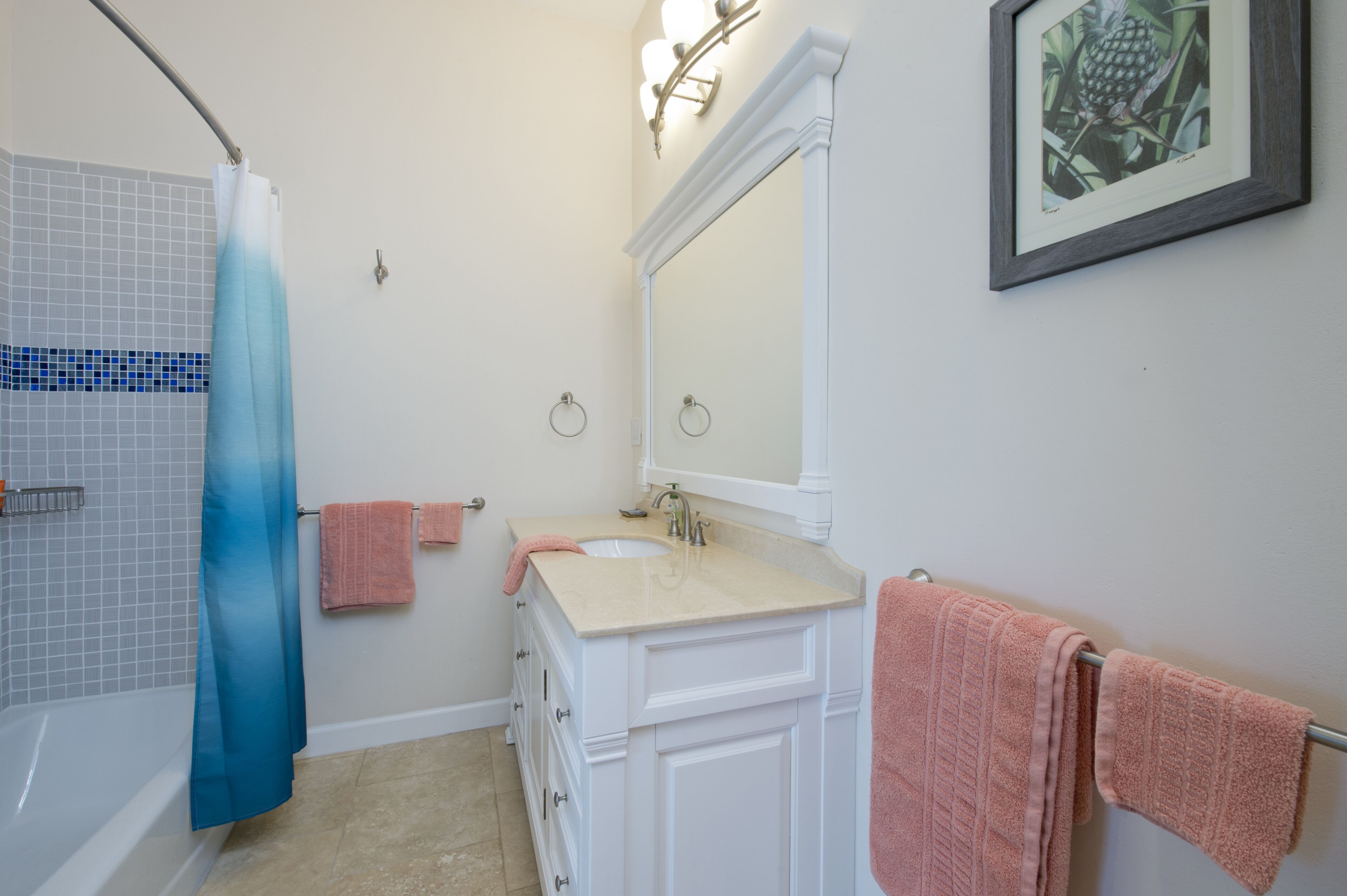 Un baño con bañera, lavamanos y espejo. Hay toallas colgadas en la pared y una cortina de ducha.
