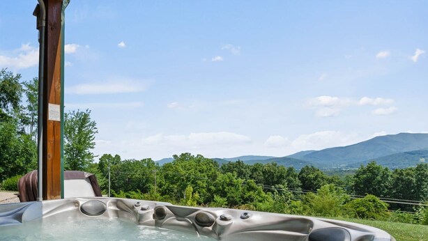 Un jacuzzi con vistas a montañas y follaje.