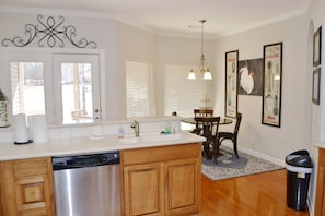 Kitchen area with central island, dishwasher, dining table, and artwork.