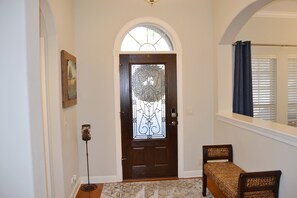 Enter a welcoming space with a dark door, vintage floor lamp, and cozy bench.