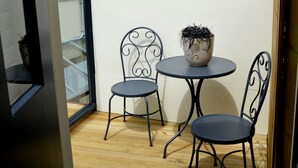 A small balcony with a round table and two chairs, a potted plant on the table, and a wooden floor. - Heritage Garden Cottage (Hobart)
