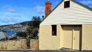 A single-story building with a beige exterior, a red brick chimney, and a small window. - Heritage Garden Cottage (Hobart)