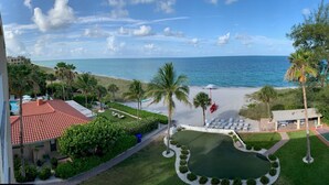 A view of a resort with a pool, tennis court, and a beach.