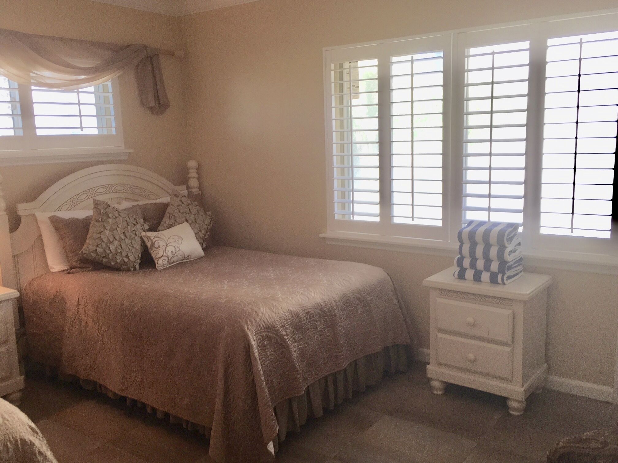 A bedroom with a bed, nightstand, and window with blinds.