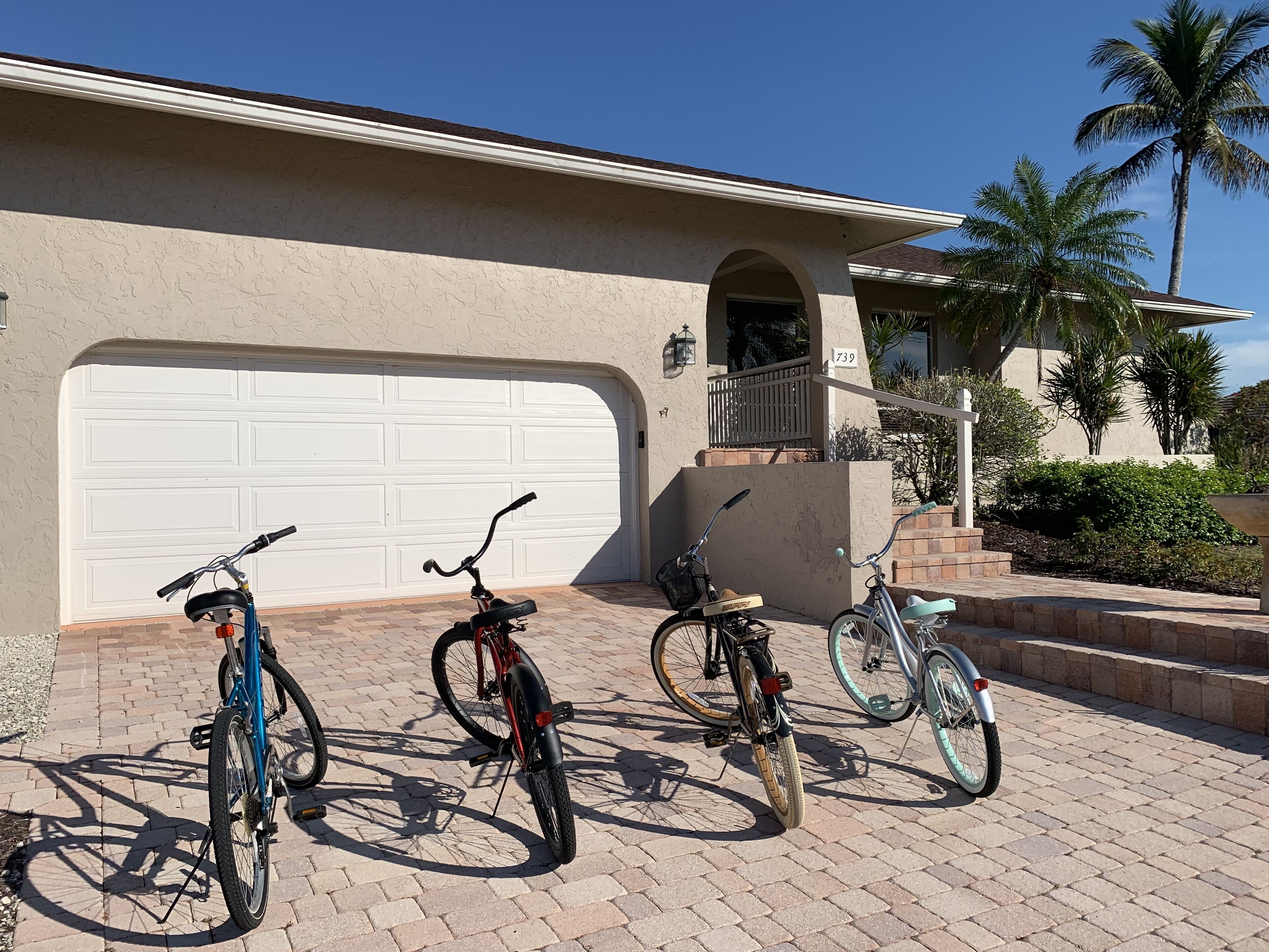 Une allée menant à une maison, avec trois vélos garés devant, et un garage attenant.
