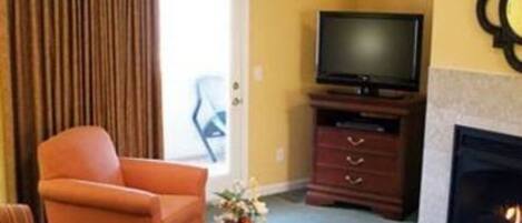 Una habitación de hotel con sofá, televisión, chimenea y un mueble de madera.