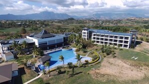 Un resort con una piscina grande, edificios modernos y vistas a montañas distantes.