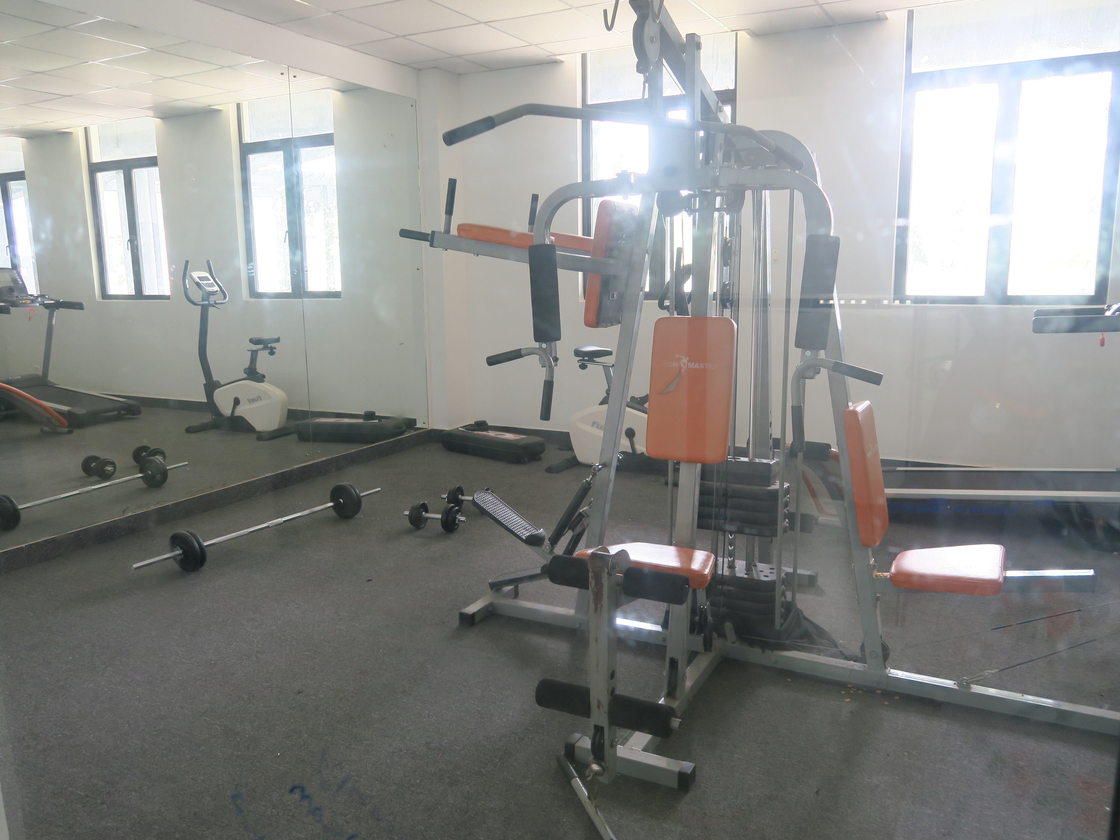 A gym with exercise equipment, mirrors, and windows.