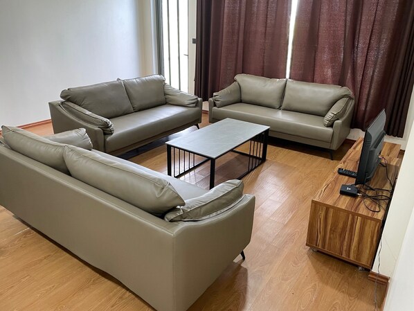 A living room with two sofas, a coffee table, and a TV stand. - Nasau Resort & Villas (Nadi)