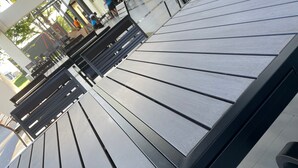 Un espacio al aire libre moderno con bancos de metal y barandilla de vidrio.