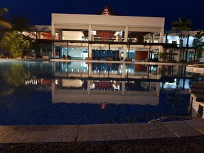 A modern hotel with a large pool reflecting the building and palm trees. - Nasau Resort & Villas (Nadi)