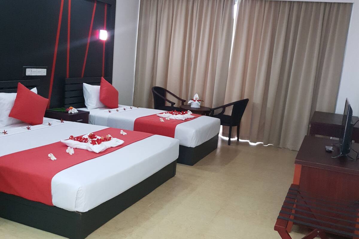 A hotel room with two beds, a desk, and a chair.