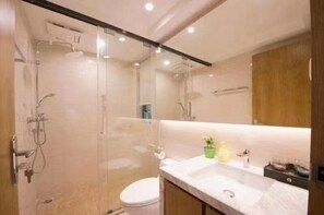 Une salle de bain moderne avec une douche à parois de verre, des toilettes blanches et un meuble-lavabo avec un miroir et un évier.