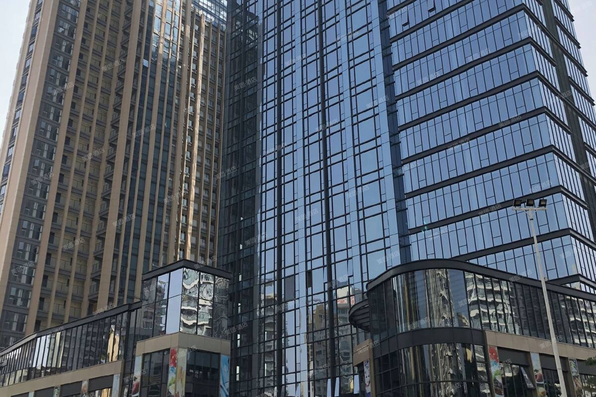Ein modernes Hochhaus mit verglasten Fassaden und einem geschwungenen Eingang.