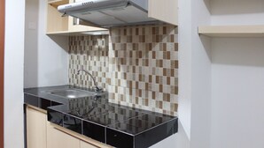 Una cocina con encimera negra, un lavamanos y salpicadero de azulejos.