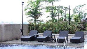 Zona de piscina en la azotea con sillones y vistas a la ciudad.