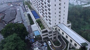 Un edificio de gran altura con varios pisos, una piscina en la azotea y un camino de entrada curvo.